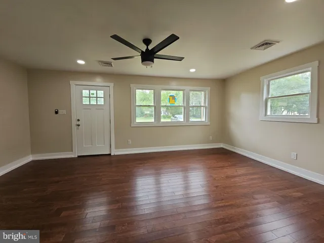 a view of an empty room with wooden floor and a window