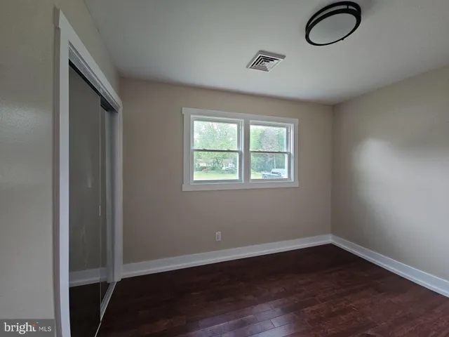 an empty room with wooden floor cabinet and windows