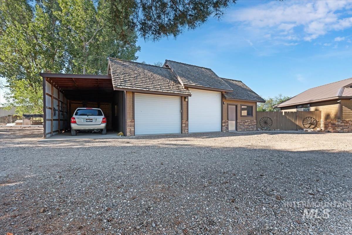 8275 Washoe Road Fruitland, ID 83619 - Photo 27 of 43 Gravel driveway leading to a two-car garage with white garage doors and an attached carport