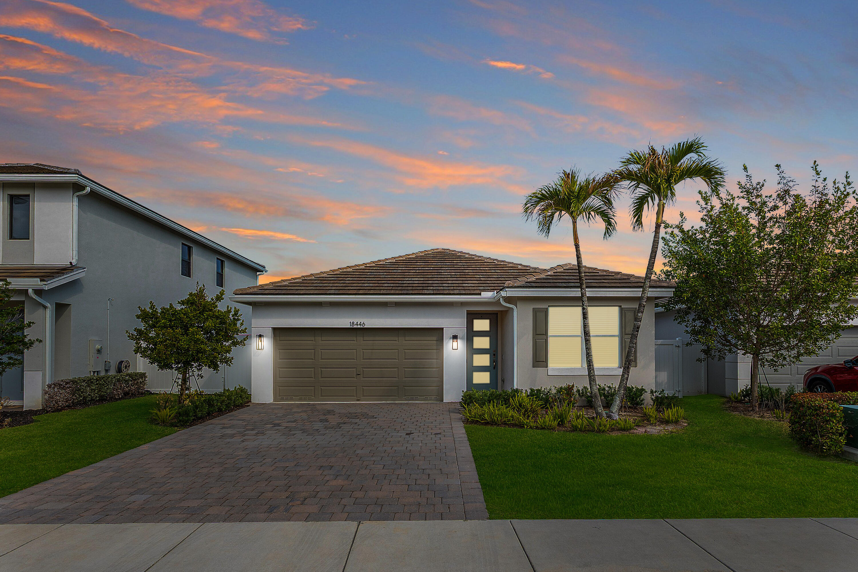 front view of a house with a yard and palm trees