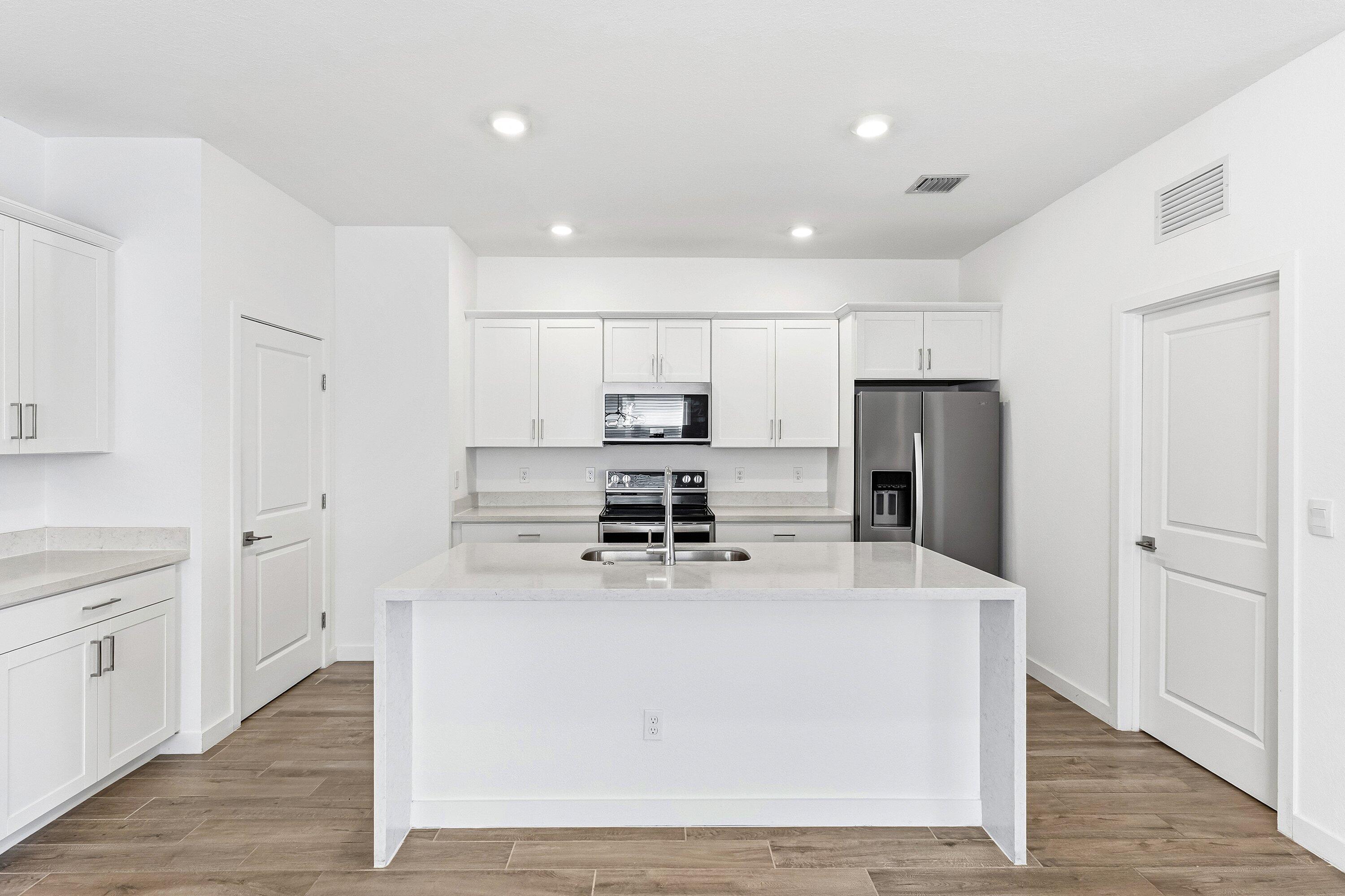 18446 Claybrook Street Jupiter, FL 33458 - Photo 5 of 25 a kitchen with stainless steel appliances a refrigerator sink and white cabinets