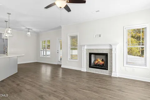 a view of an empty room with wooden floor fireplace and a window