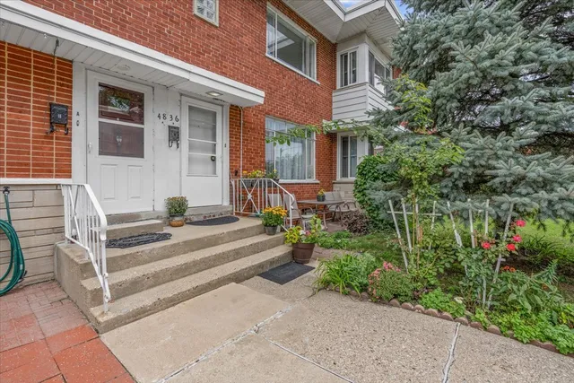 a view of a house with potted plants and a bench