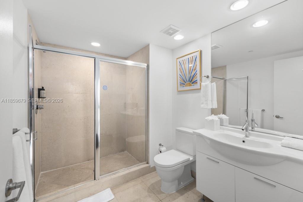 485 Brickell Avenue, Unit 2210 Miami, FL 33131 - Photo 27 of 71 a bathroom with a toilet a sink a glass door a shower a mirror and vanity