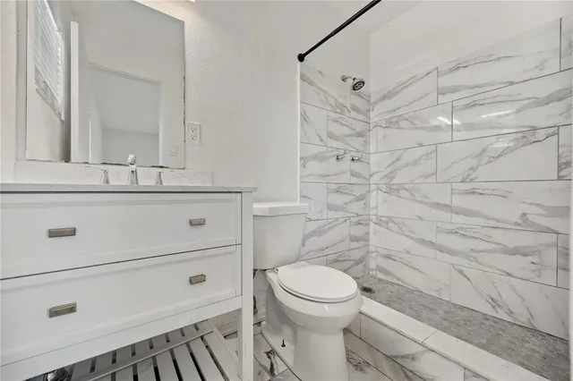 a bathroom with a granite countertop toilet sink and mirror