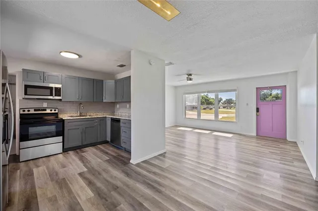 a kitchen with stainless steel appliances granite countertop a refrigerator a stove top oven a sink dishwasher and wooden floor