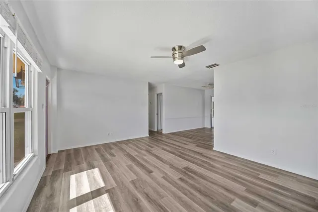 a view of empty room with wooden floor and fan