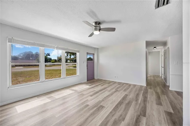 a view of an empty room with a window and wooden floor