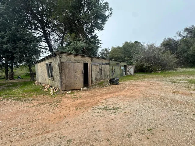 a backyard of a house with large trees and parked
