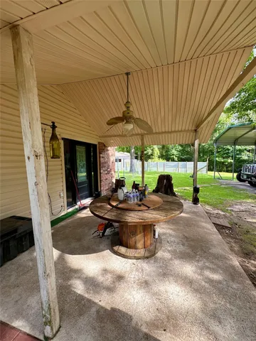 a view of a patio with table and chairs under an umbrella with a small yard