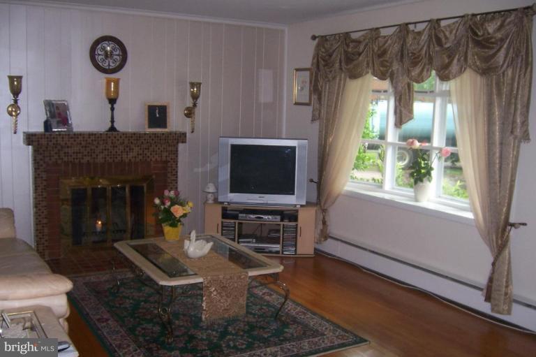 10212 Portland Road Silver Spring, MD 20901 - Photo 3 of 13 a living room with furniture a flat screen tv and a fireplace
