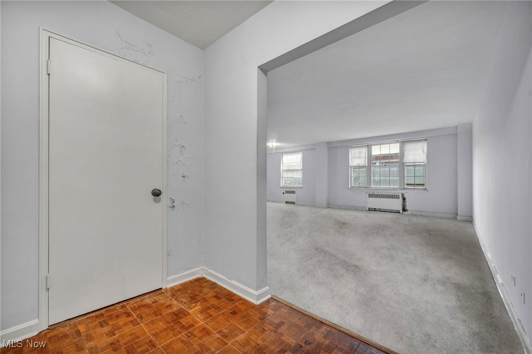 Carpeted foyer entrance with radiator heating unit