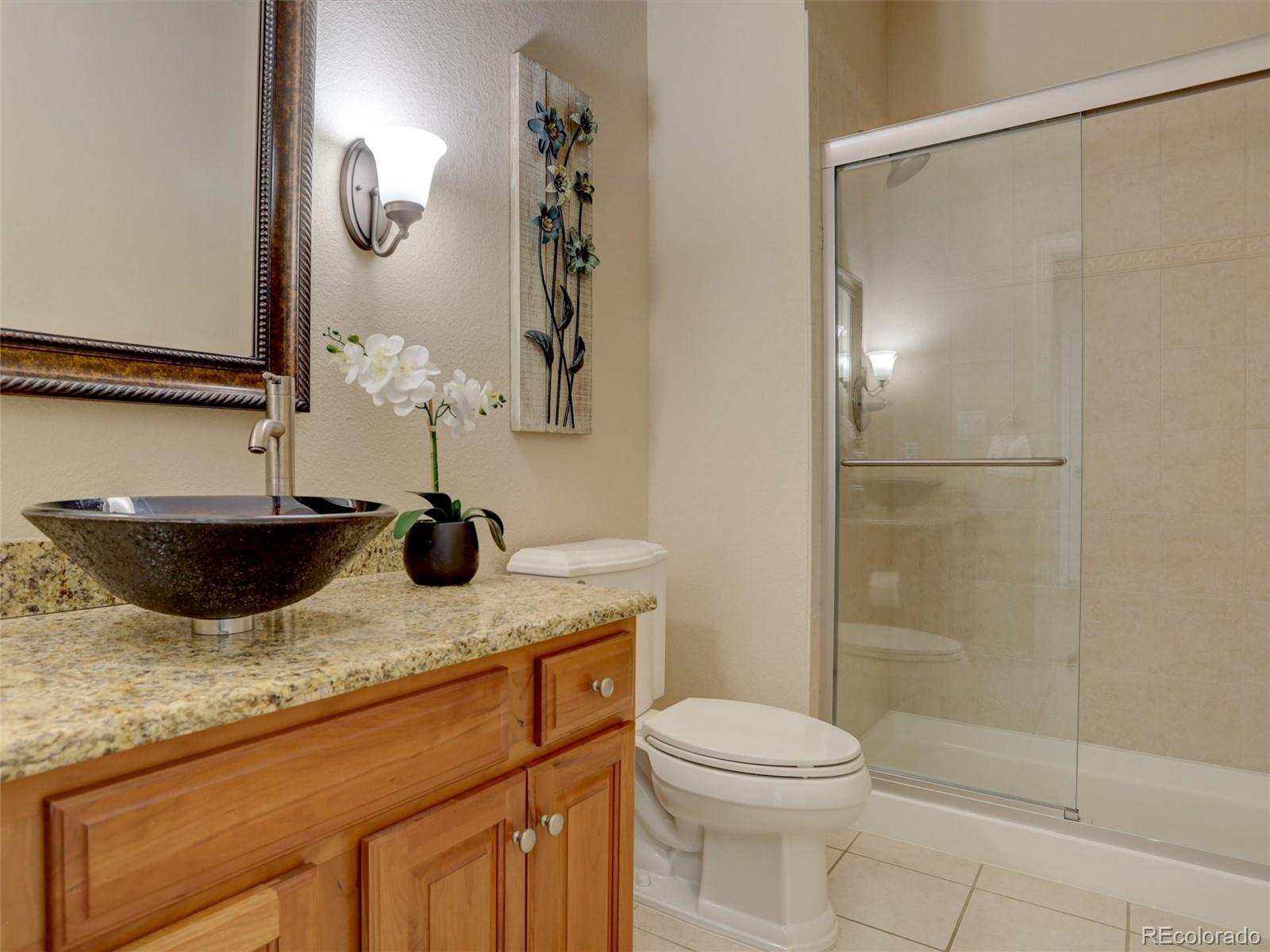 18288 East Caley Place Aurora, CO 80016 - Photo 14 of 50 a bathroom with a granite countertop sink a toilet and shower