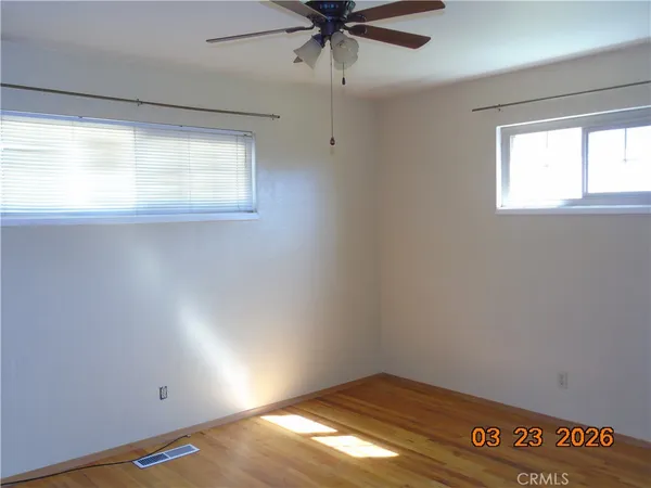 a view of an empty room with wooden floor and closet