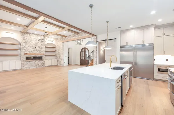 a large kitchen with kitchen island a stove a sink a refrigerator and a wooden floor