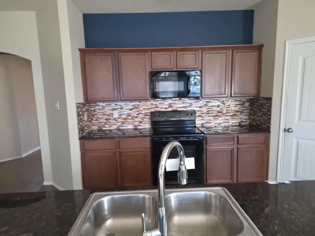 a kitchen with granite countertop a sink stainless steel appliances and cabinets