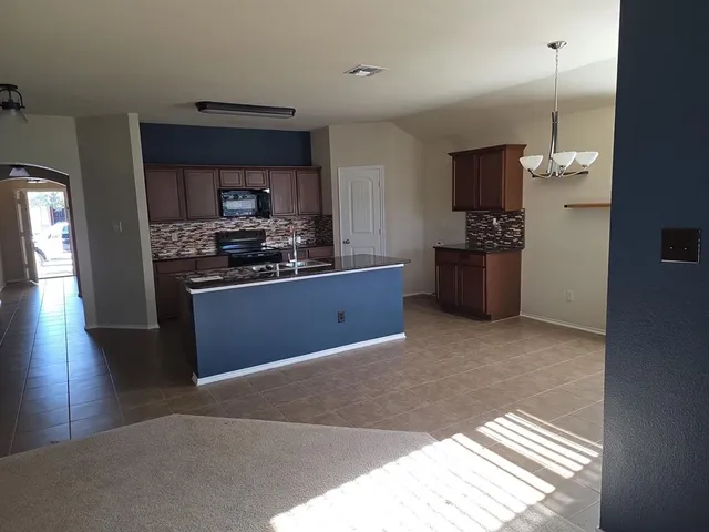 a kitchen with stainless steel appliances granite countertop a refrigerator a sink a stove and a wooden floors