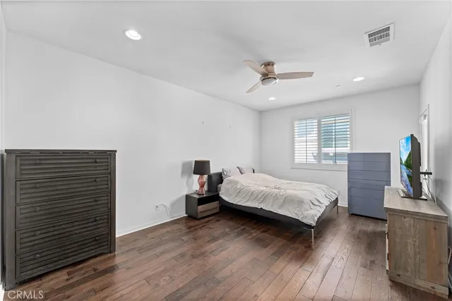 a spacious bedroom with a bed and wooden floor