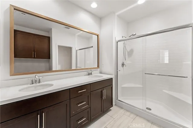 a bathroom with a double vanity sink mirror and shower