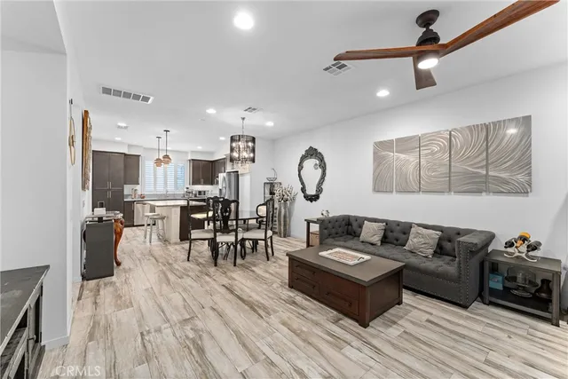 a living room with furniture kitchen view and a wooden floor