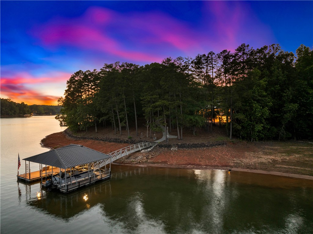 285 Bertha Allen Road Westminster, SC 29693 - Photo 42 of 50 A tranquil lakefront property featuring a private boat dock and a scenic wooded shoreline at sunset.