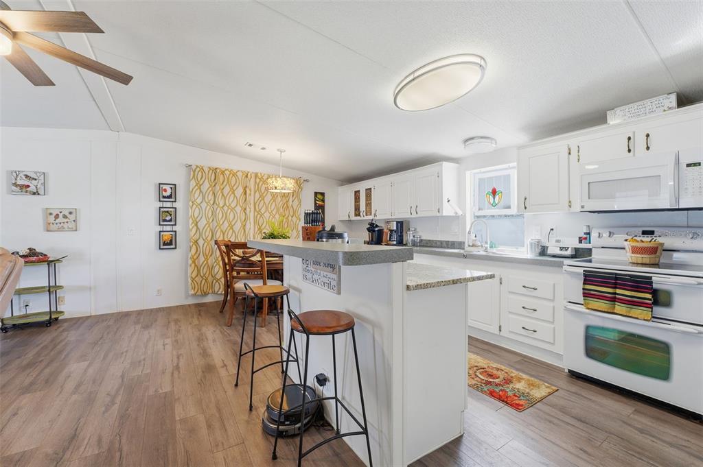 11269 Southwest Welch Avenue Arcadia, FL 34269 - Photo 11 of 41 a kitchen with stainless steel appliances granite countertop a stove top oven a sink dishwasher and white cabinets with wooden floor