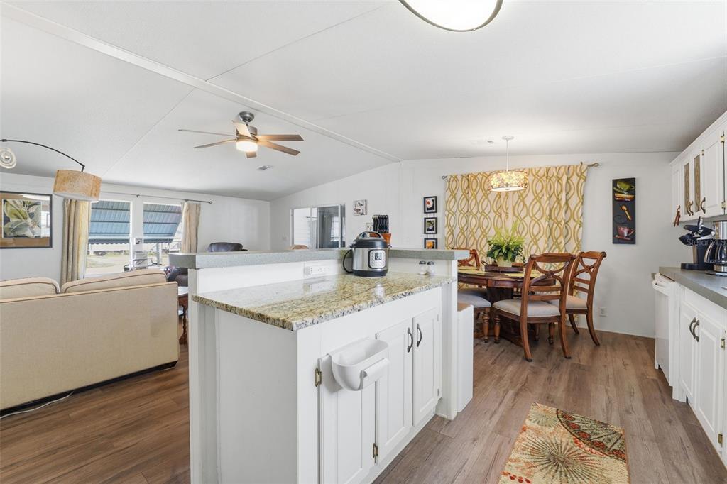 11269 Southwest Welch Avenue Arcadia, FL 34269 - Photo 12 of 41 a kitchen with granite countertop a stove a sink a dining table and chairs with wooden floor