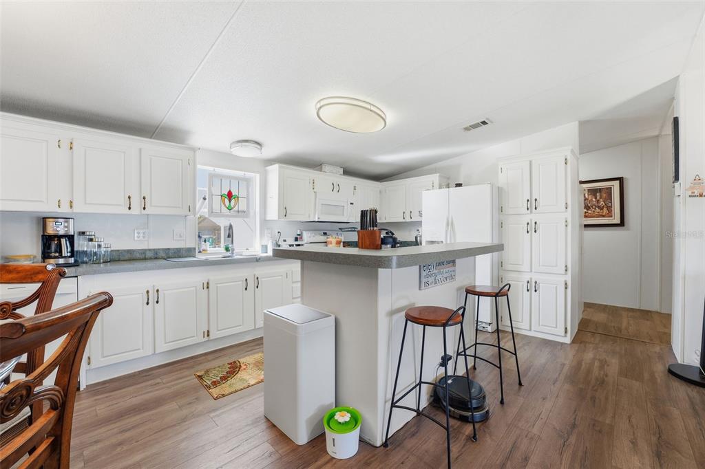 11269 Southwest Welch Avenue Arcadia, FL 34269 - Photo 10 of 41 a kitchen with stainless steel appliances granite countertop a refrigerator a stove a sink dishwasher and white cabinets with wooden floor