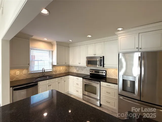 a kitchen with granite countertop a refrigerator sink and stove