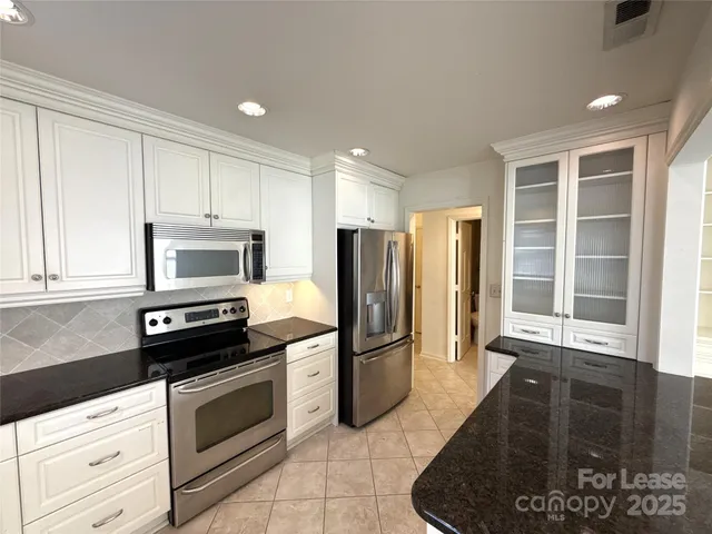 a kitchen with granite countertop a refrigerator and a stove top oven