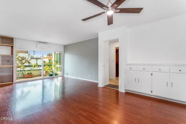 an empty room with wooden floor chandelier fan and windows
