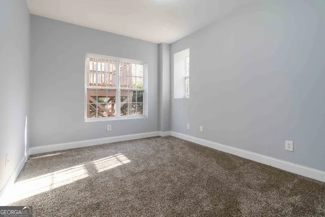 a view of an empty room with a window and a kitchen