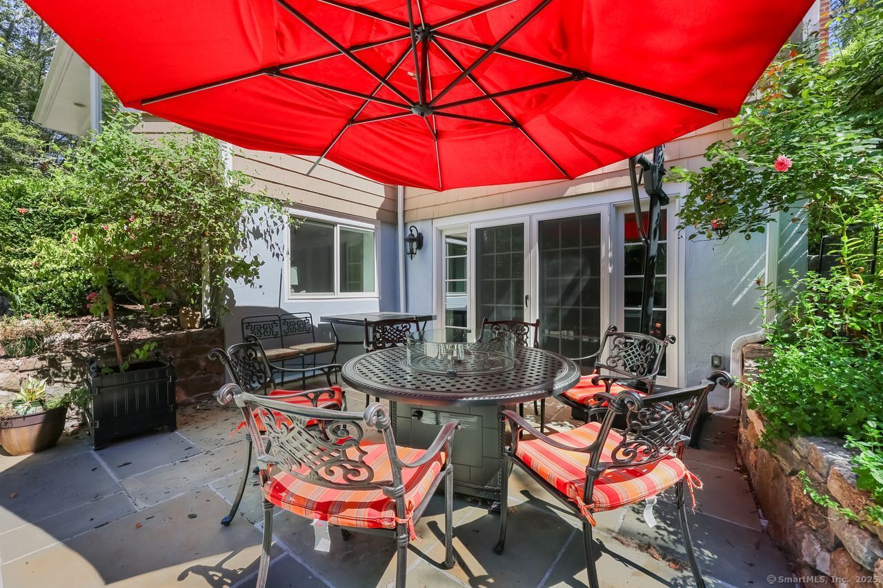 176 Logan Road New Canaan, CT 06840 - Photo 34 of 40 a patio with a table and chairs under an umbrella