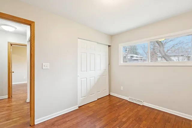 a view of empty room with wooden floor and fan
