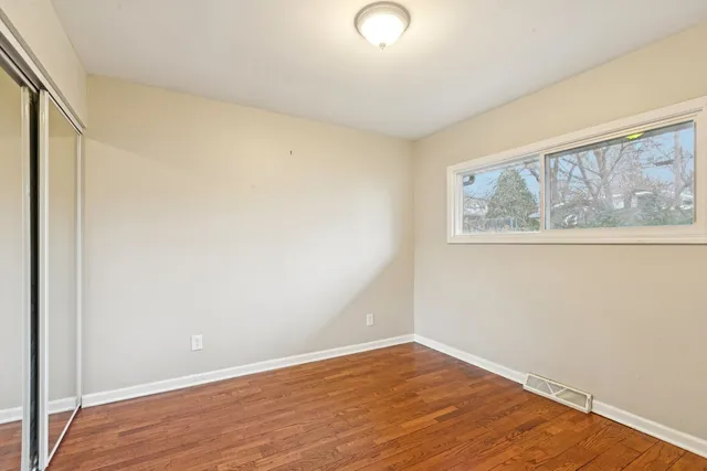 an empty room with wooden floor and mirror
