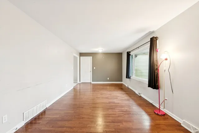 a view of an empty room with wooden floor and a large window