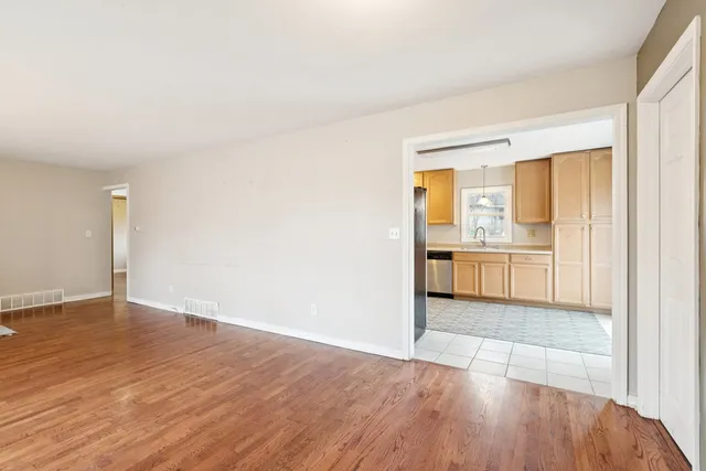 an empty room with wooden floor cabinet and windows
