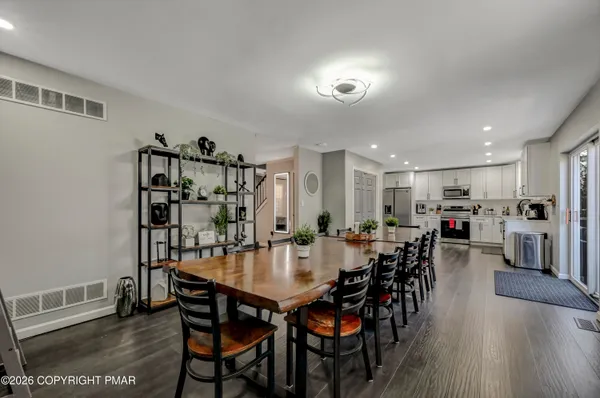 a view of a dining room and livingroom with furniture wooden floor a rug a painting and a chandelier