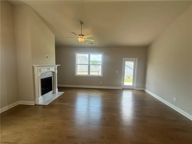 an empty room with wooden floor fireplace and windows