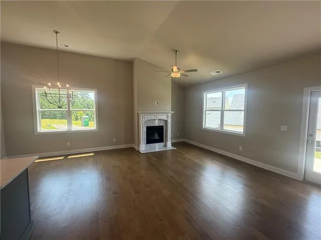 an empty room with wooden floor fireplace and windows