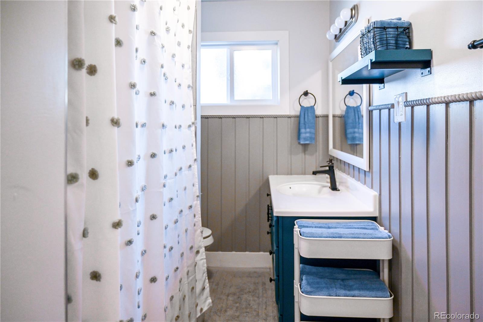 7051 Ruth Way Denver, CO 80221 - Photo 19 of 36 a bathroom with a sink a toilet and shower curtain