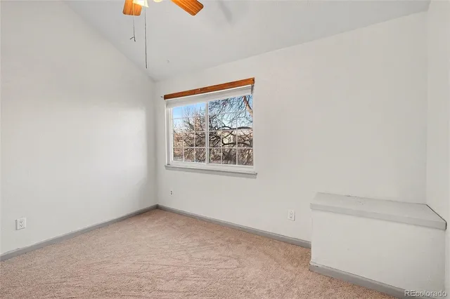 an empty room with a window and a ceiling fan