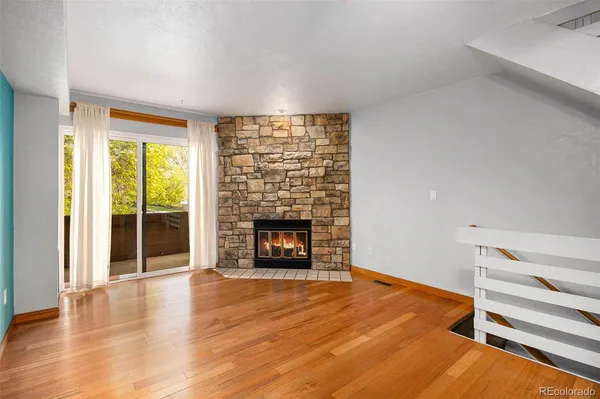 an empty room with wooden floor fireplace and windows