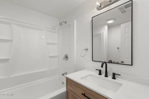 a bathroom with a bathtub shower sink vanity and a mirror