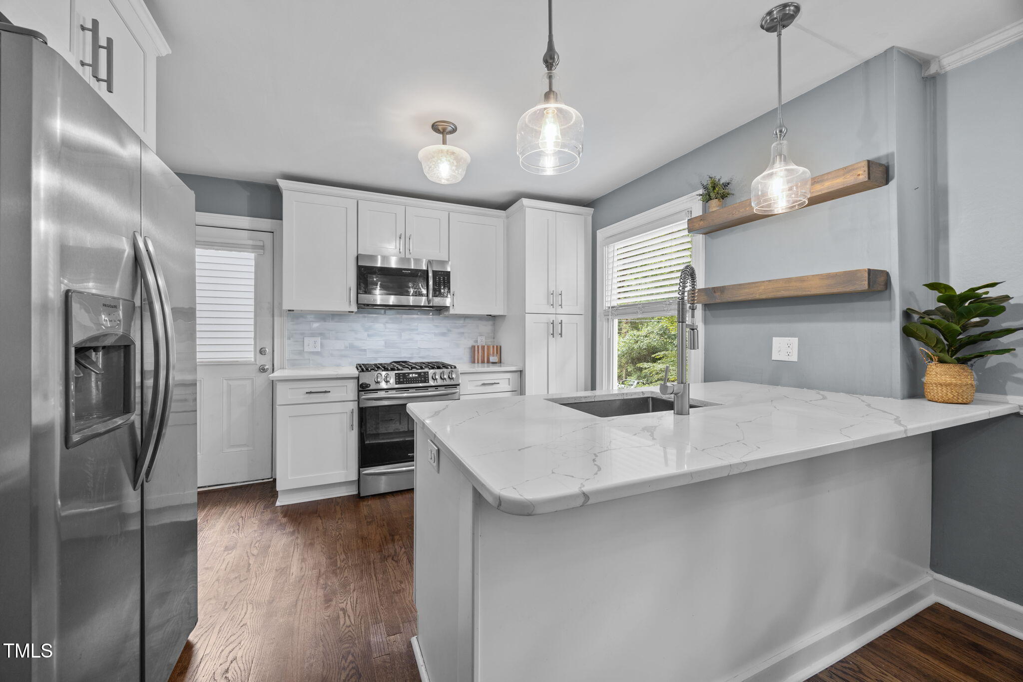 2721 Cartier Drive Raleigh, NC 27608 - Photo 7 of 44 a kitchen with stainless steel appliances granite countertop a sink a stove a refrigerator and island with wooden floor