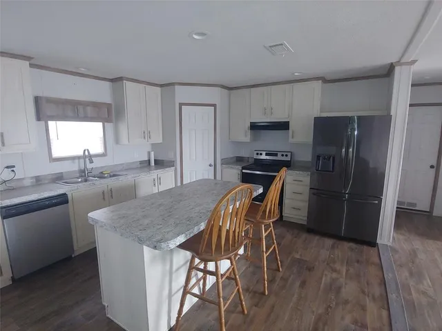 a kitchen with stainless steel appliances granite countertop a kitchen island hardwood floor sink and stove