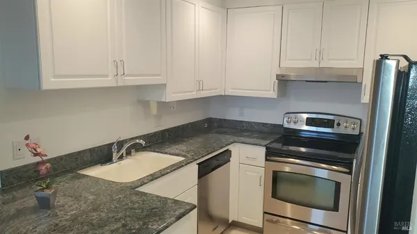 a kitchen with granite countertop white cabinets and stainless steel appliances