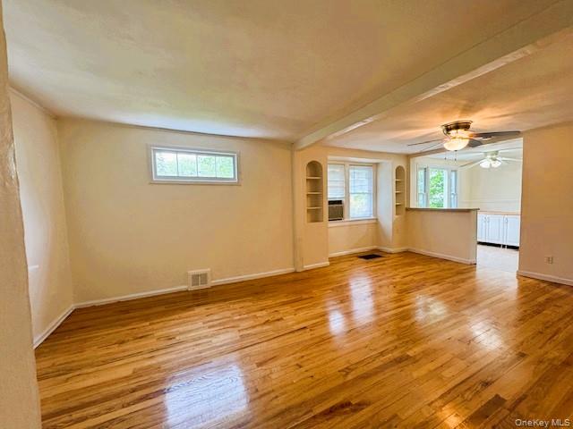 42 Hamilton Road, Unit LEFT North Merrick, NY 11566 - Photo 12 of 24 Living area featuring wood-finish flooring, built-in shelving, multiple windows providing natural light, and a ceiling fan