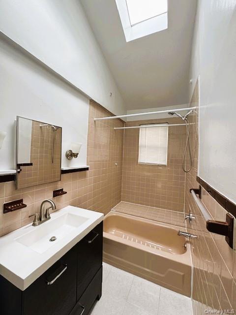 42 Hamilton Road, Unit LEFT North Merrick, NY 11566 - Photo 14 of 24 Bathroom featuring a skylight, a dark-finish vanity with a white countertop, a mirror, and a beige tiled shower/tub combination