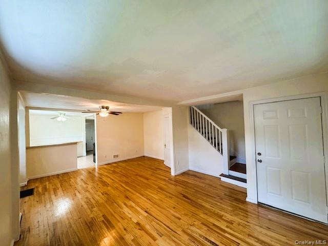 42 Hamilton Road, Unit LEFT North Merrick, NY 11566 - Photo 23 of 24 Hardwood flooring in a spacious room featuring a white paneled entry door and a staircase with white balusters